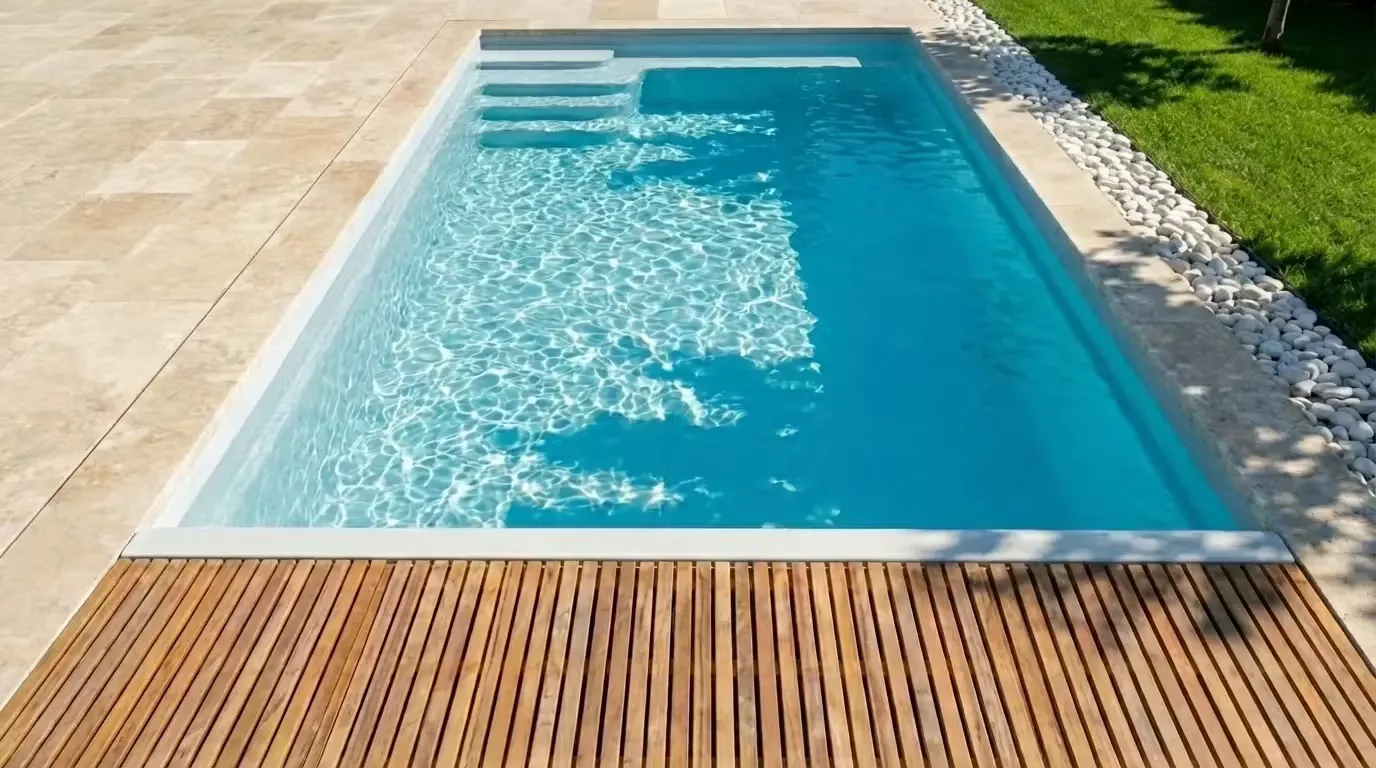 Piscine coque rectangulaire avec emplacement de volet immergé sur petit côté, margelles en travertin et deck bois