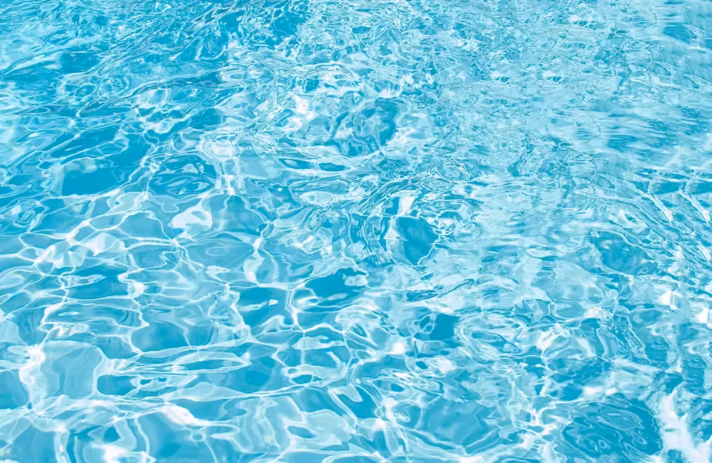 Gros plan sur la surface ondulée de l'eau d'une piscine, reflets et nuances de bleu turquoise