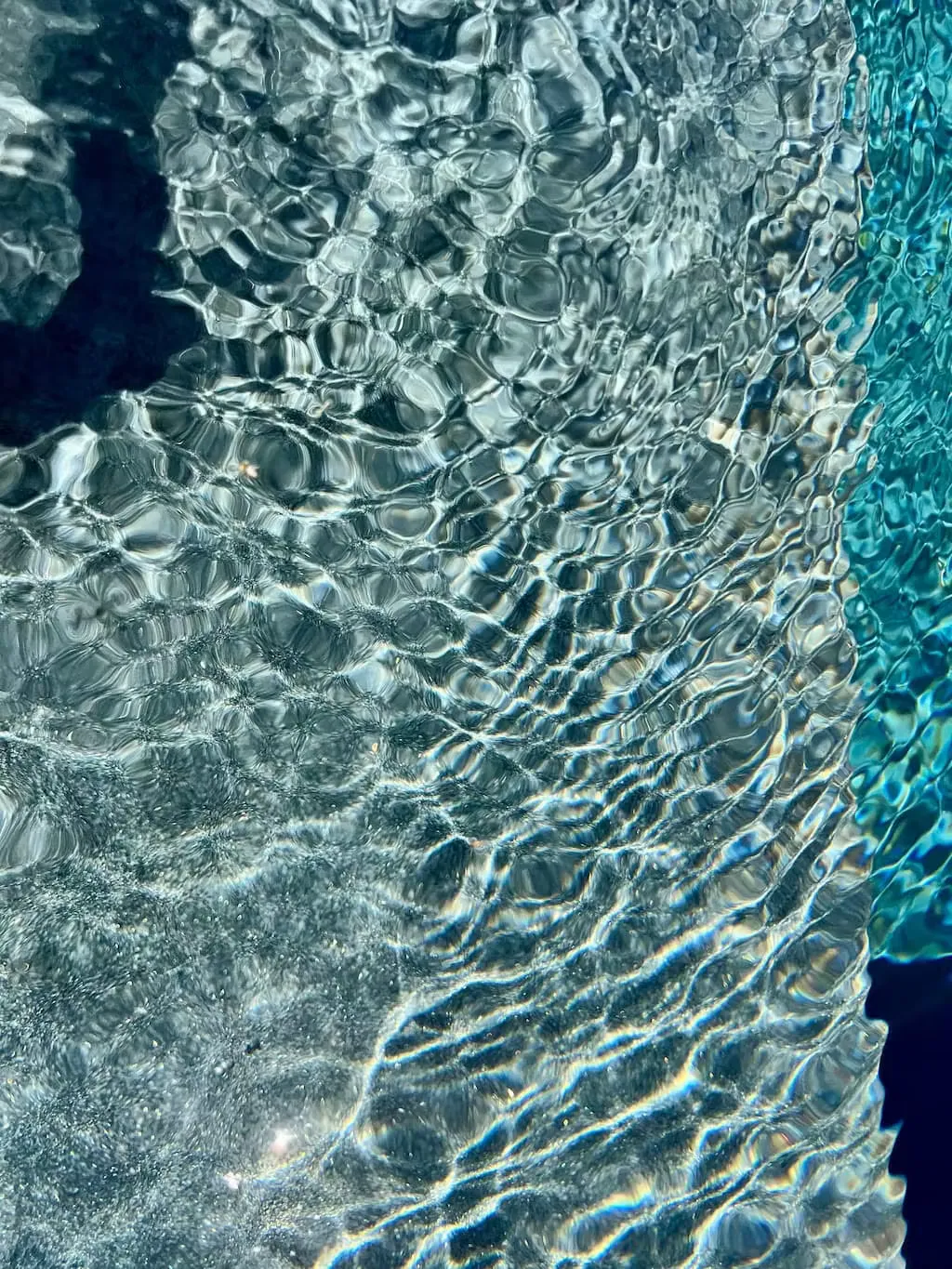 Détail rapproché de l'eau d'une piscine équipée de la finition Mineral Coat, reflets et clapotis caractéristiques