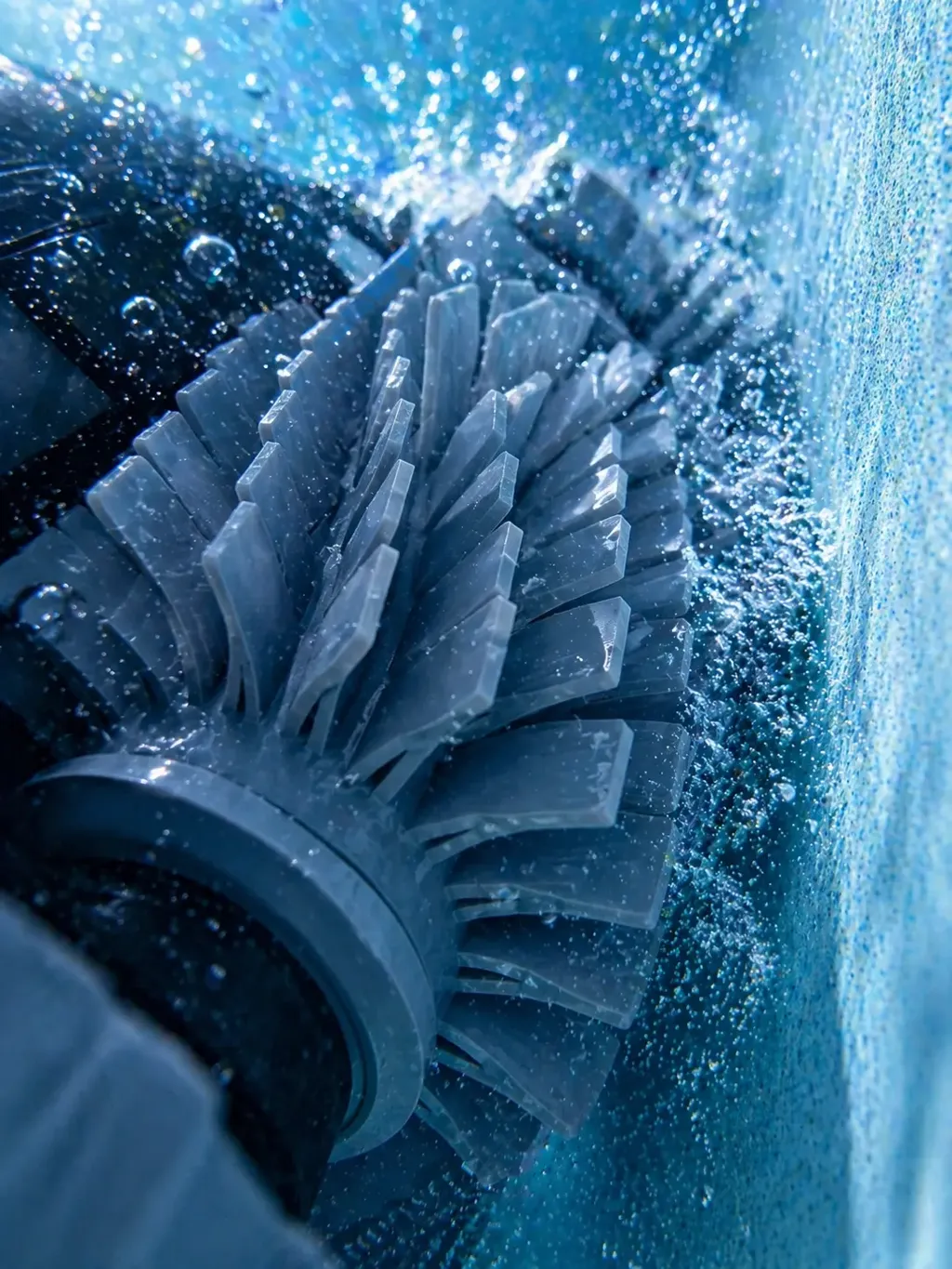 Détail rapproché de la brosse cylindrique d'un robot de nettoyage en action dans une piscine