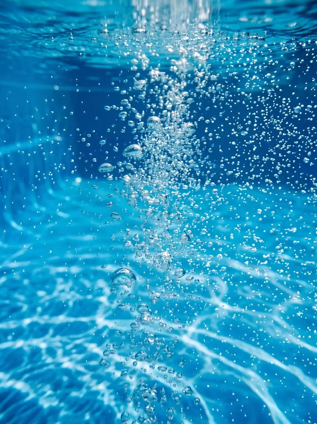 Vue sous-marine de bulles d'air remontant dans l'eau bleue d'une piscine