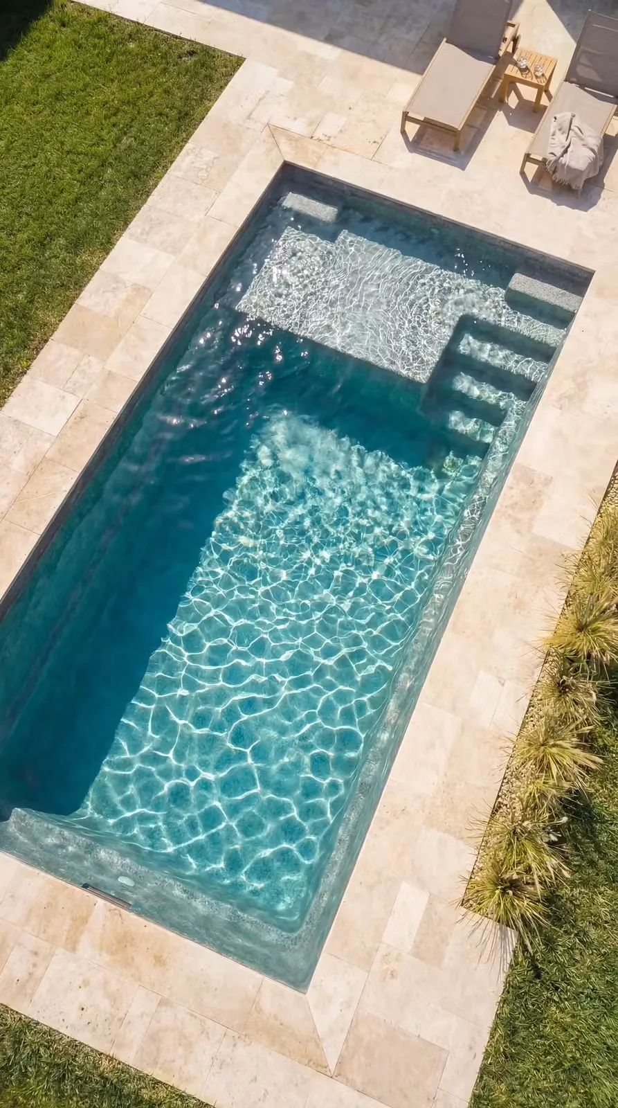 Vue aérienne du modèle Plage 850 avec escalier d'angle et plage immergée, margelles en travertin