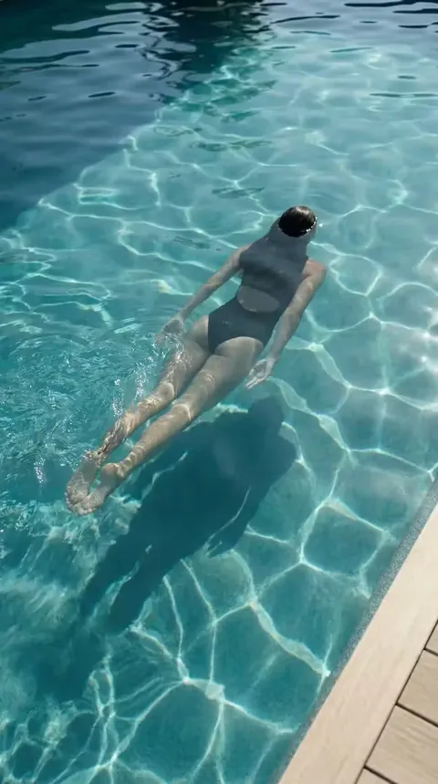 Vue plongeante d'une nageuse en maillot foncé en immersion à la surface d'une piscine à eau claire